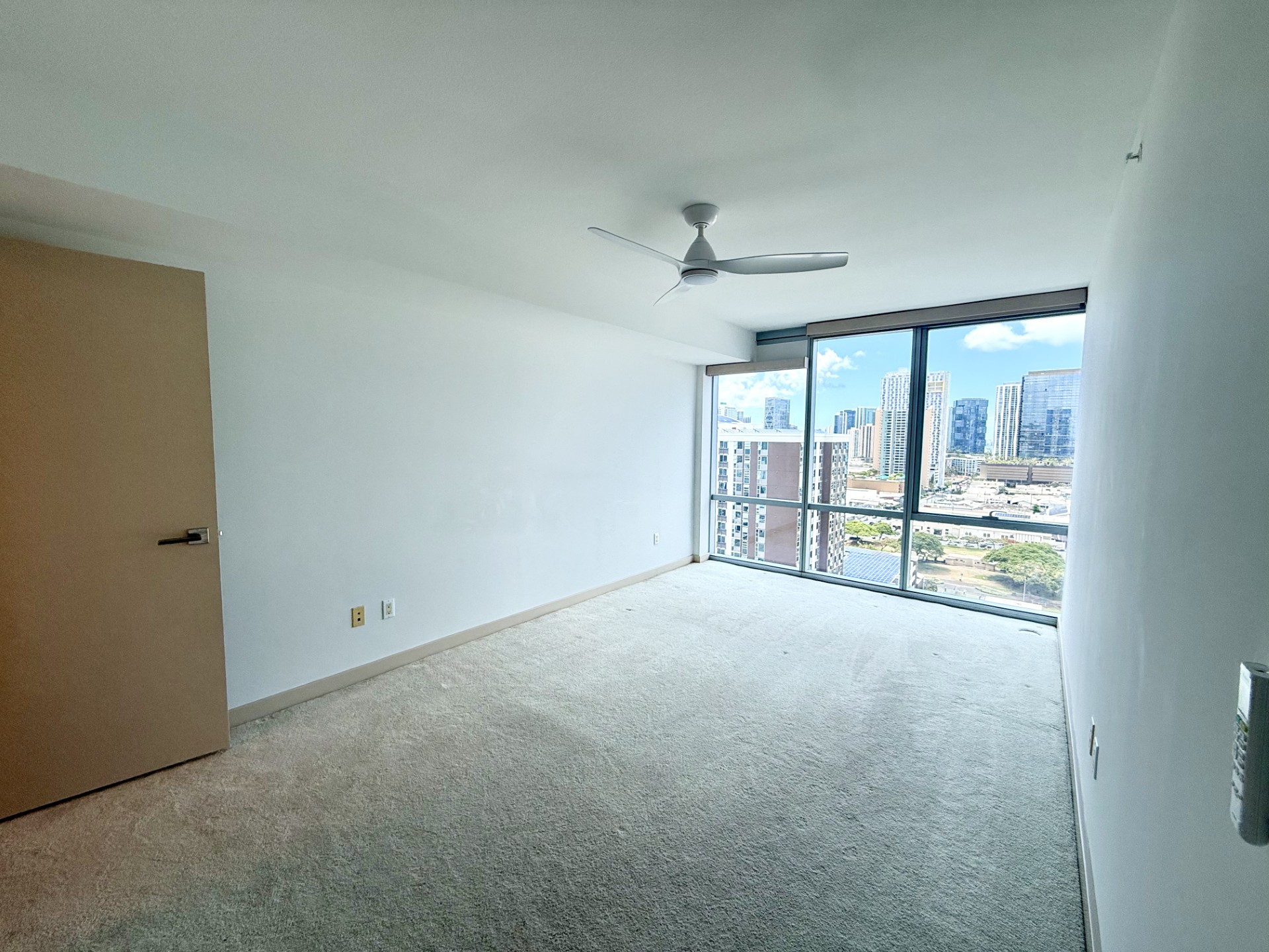 A room with a ceiling fan and a view of the city.