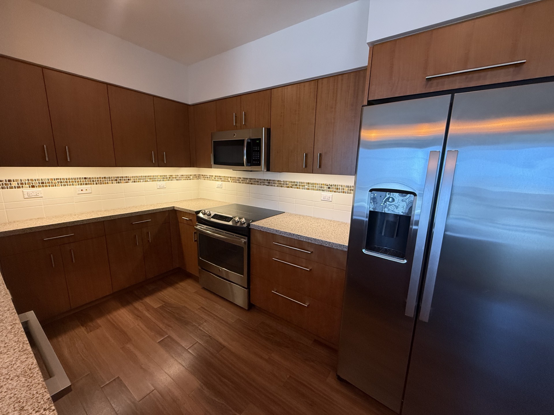A kitchen with a refrigerator, oven, and microwave.