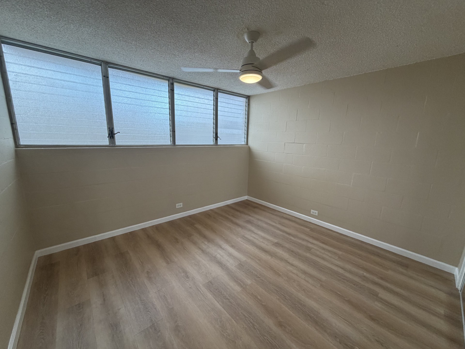A room with a ceiling fan and a window with blinds.