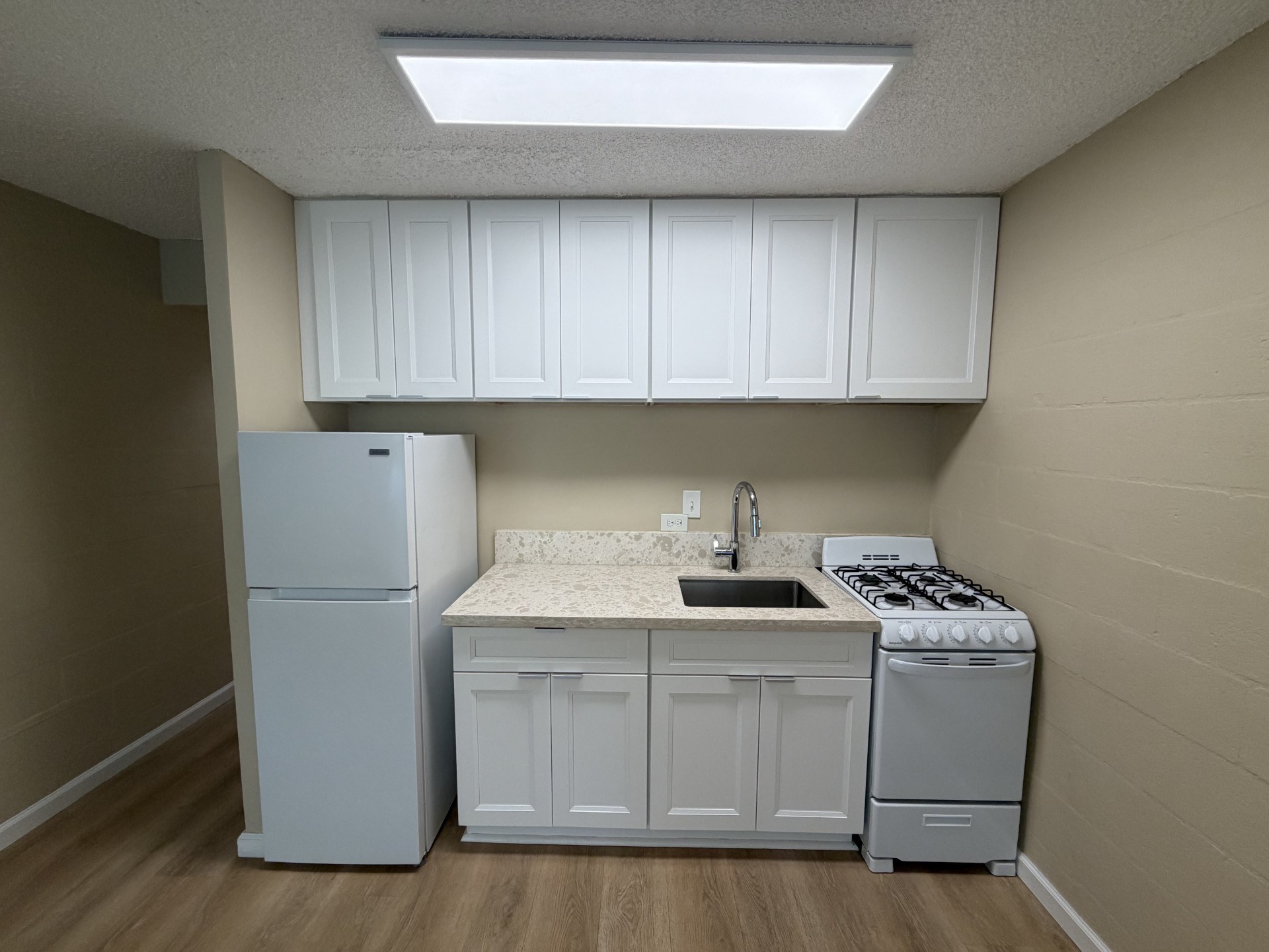 A small kitchen with a refrigerator, stove, and cabinets.