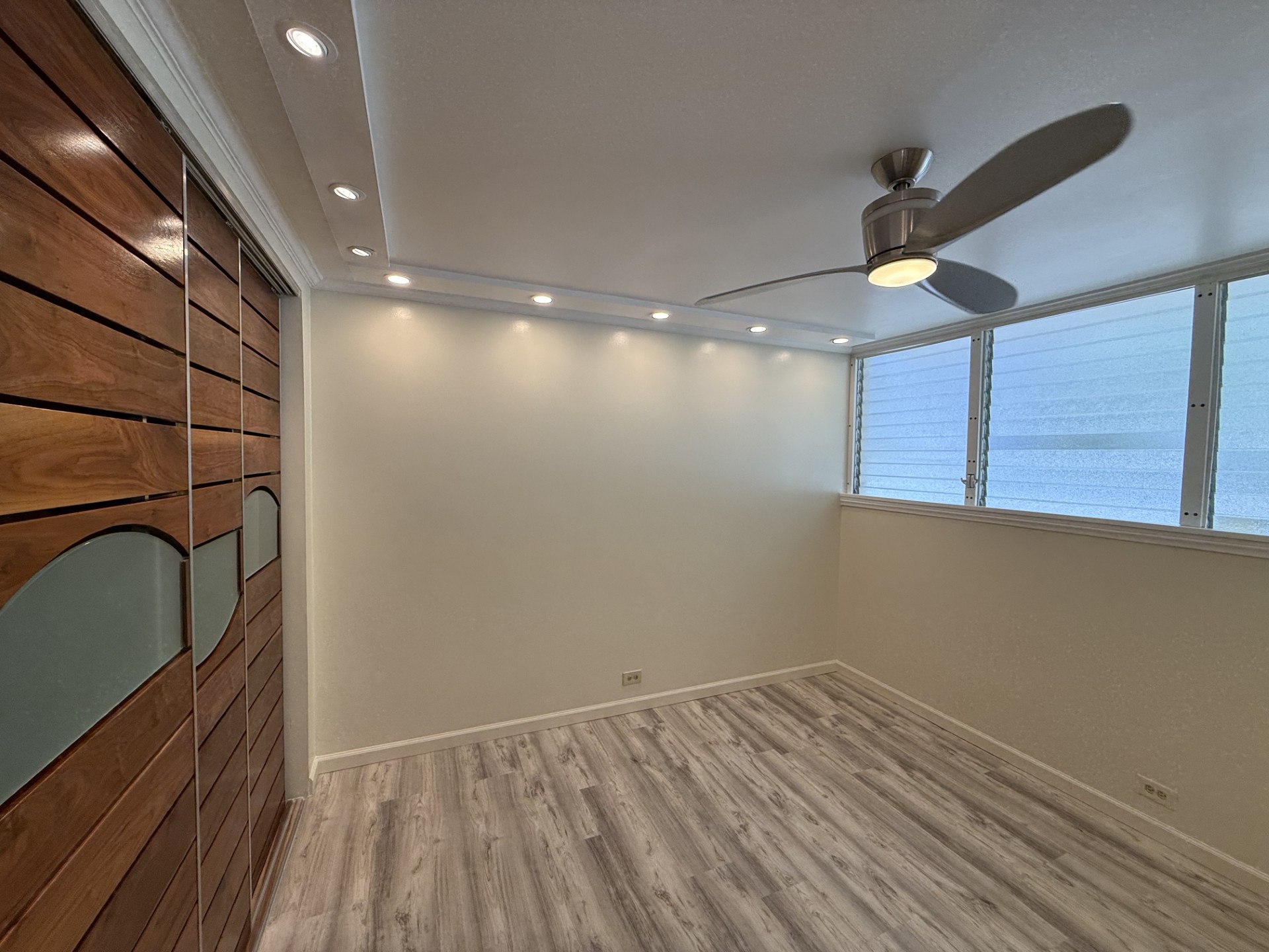 A room with a ceiling fan and wooden flooring.