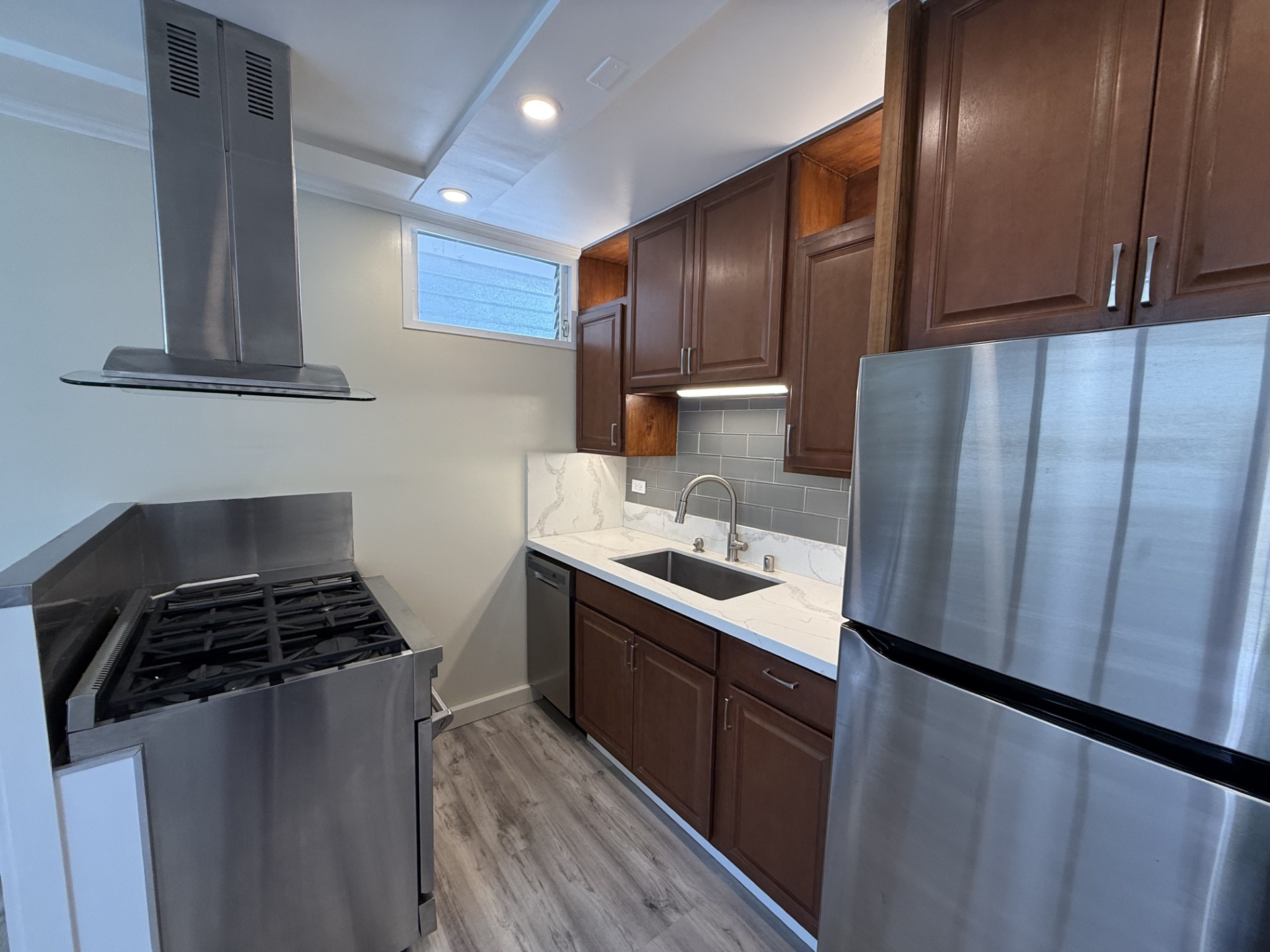 A modern kitchen with a stainless steel refrigerator, oven, and cabinets.