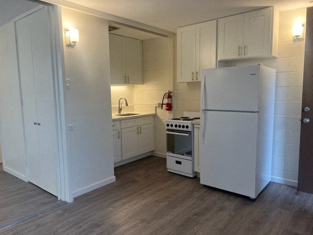 a white kitchen with a refrigerator and a stove