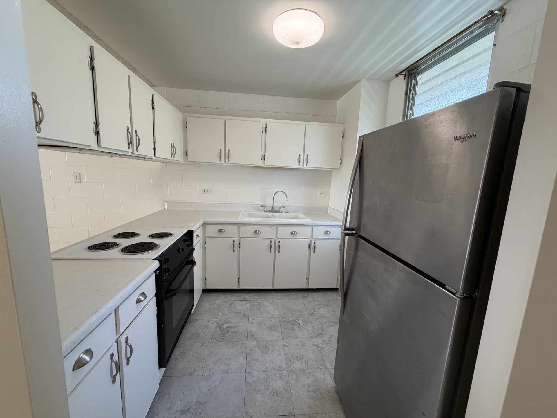 A kitchen with white cabinets and a black refrigerator.