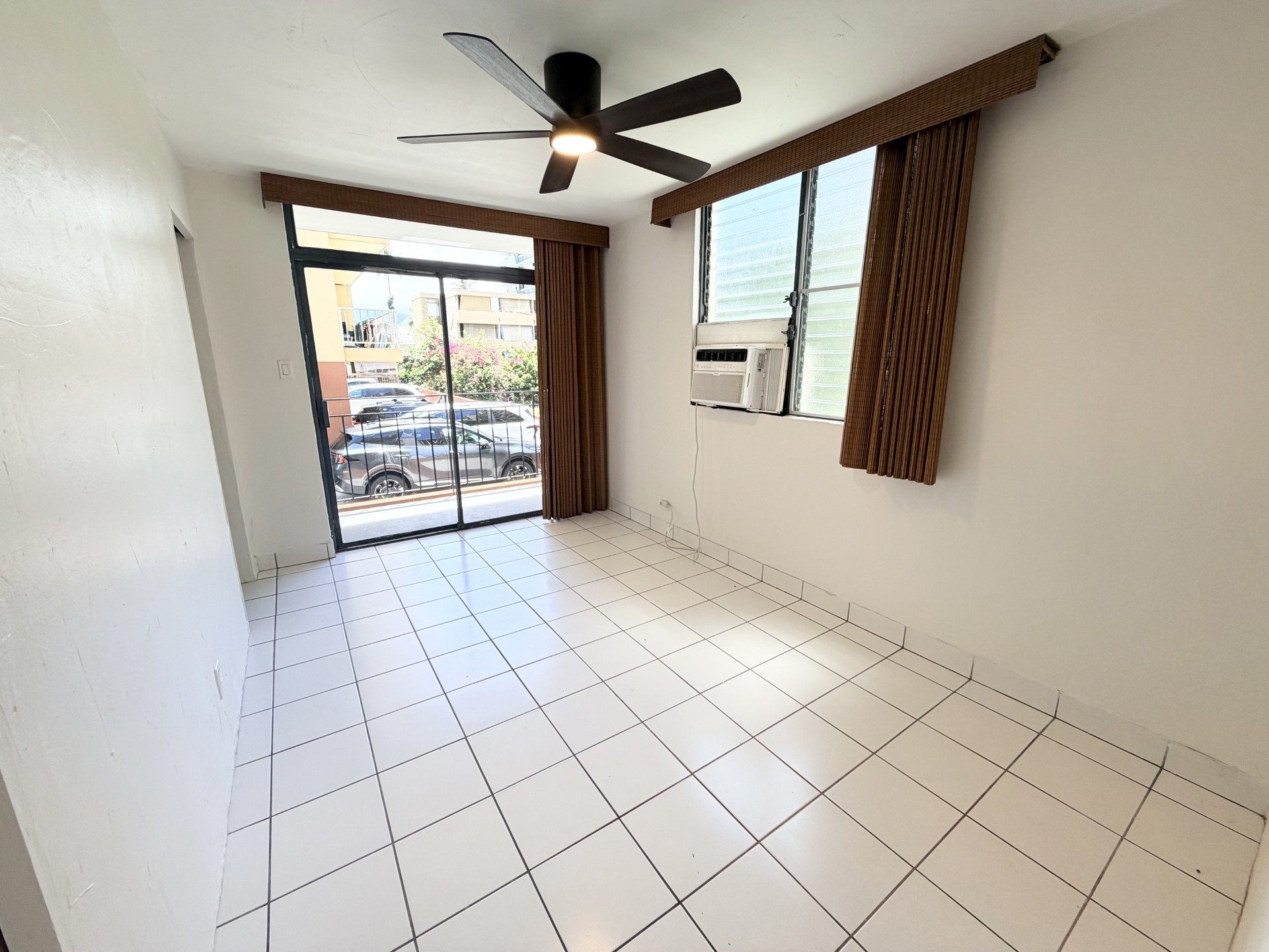 A room with a ceiling fan and sliding glass doors.