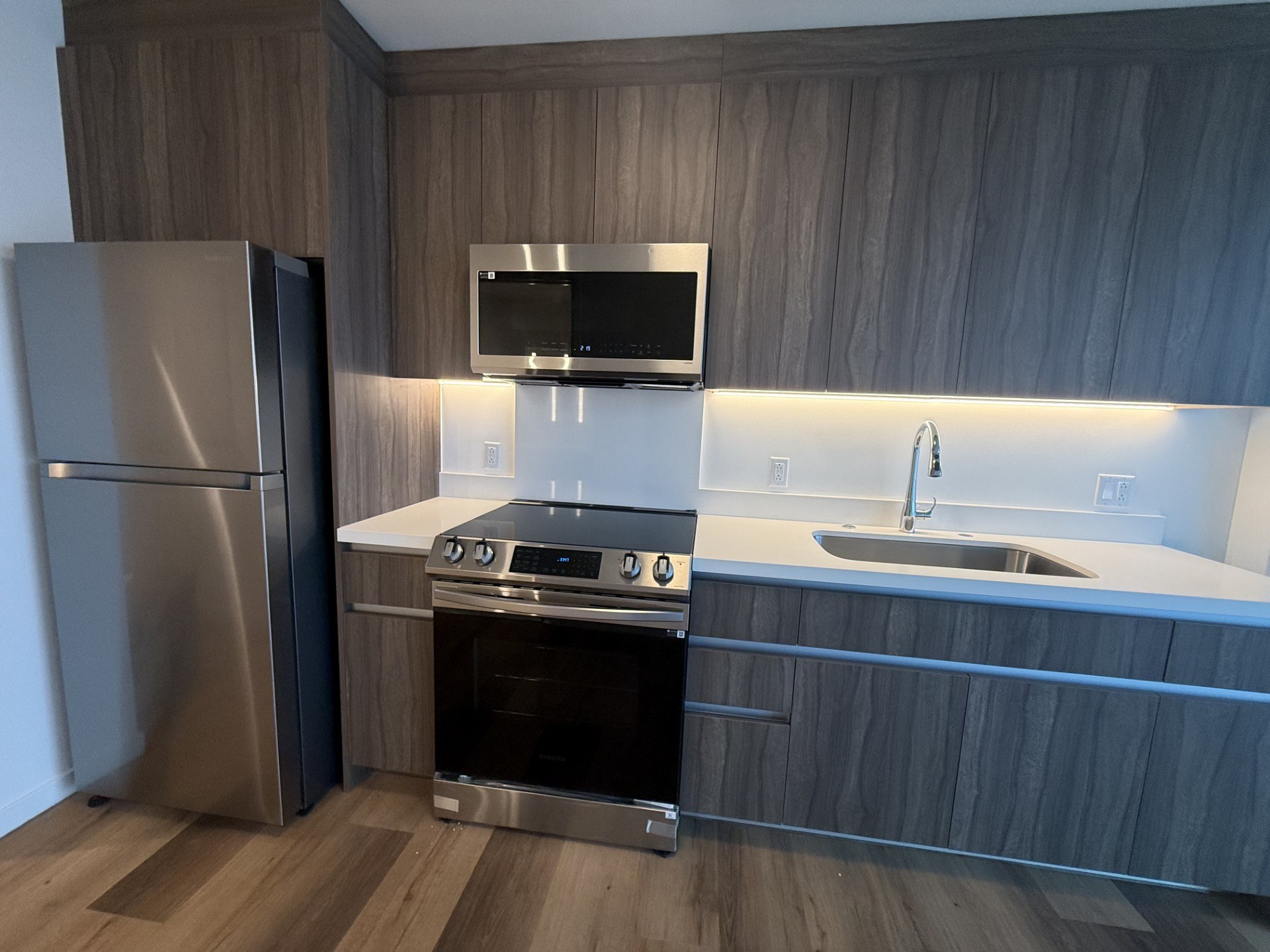 A modern kitchen with a stainless steel refrigerator and oven.