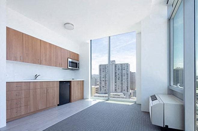 an empty room with a large window and a kitchen