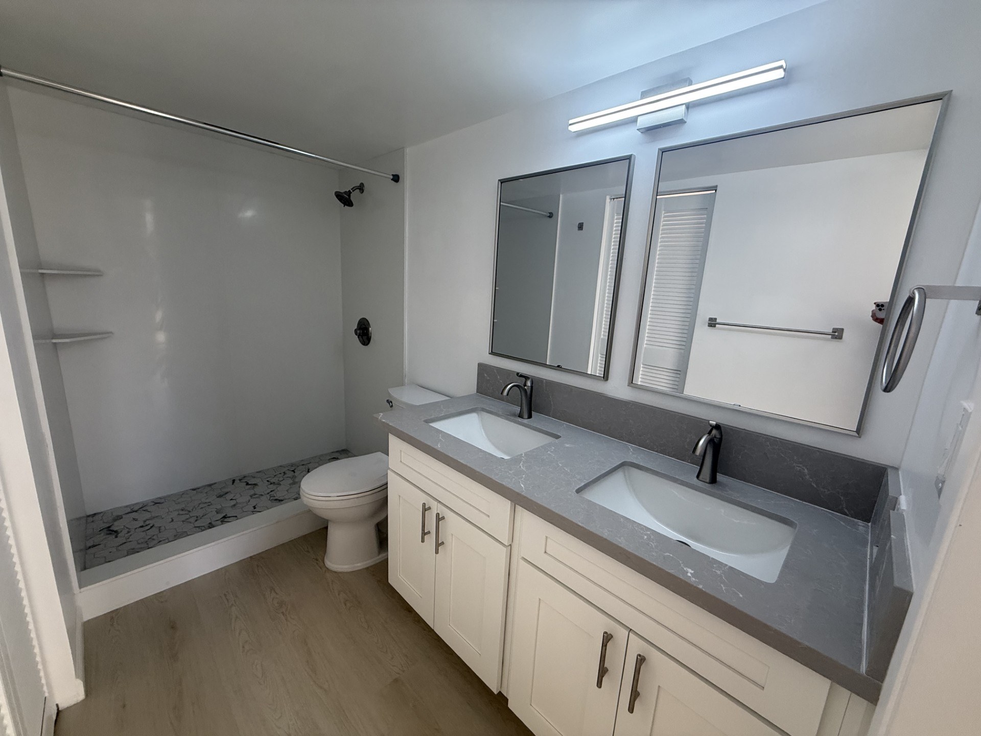 A bathroom with a toilet, sink, and mirror.