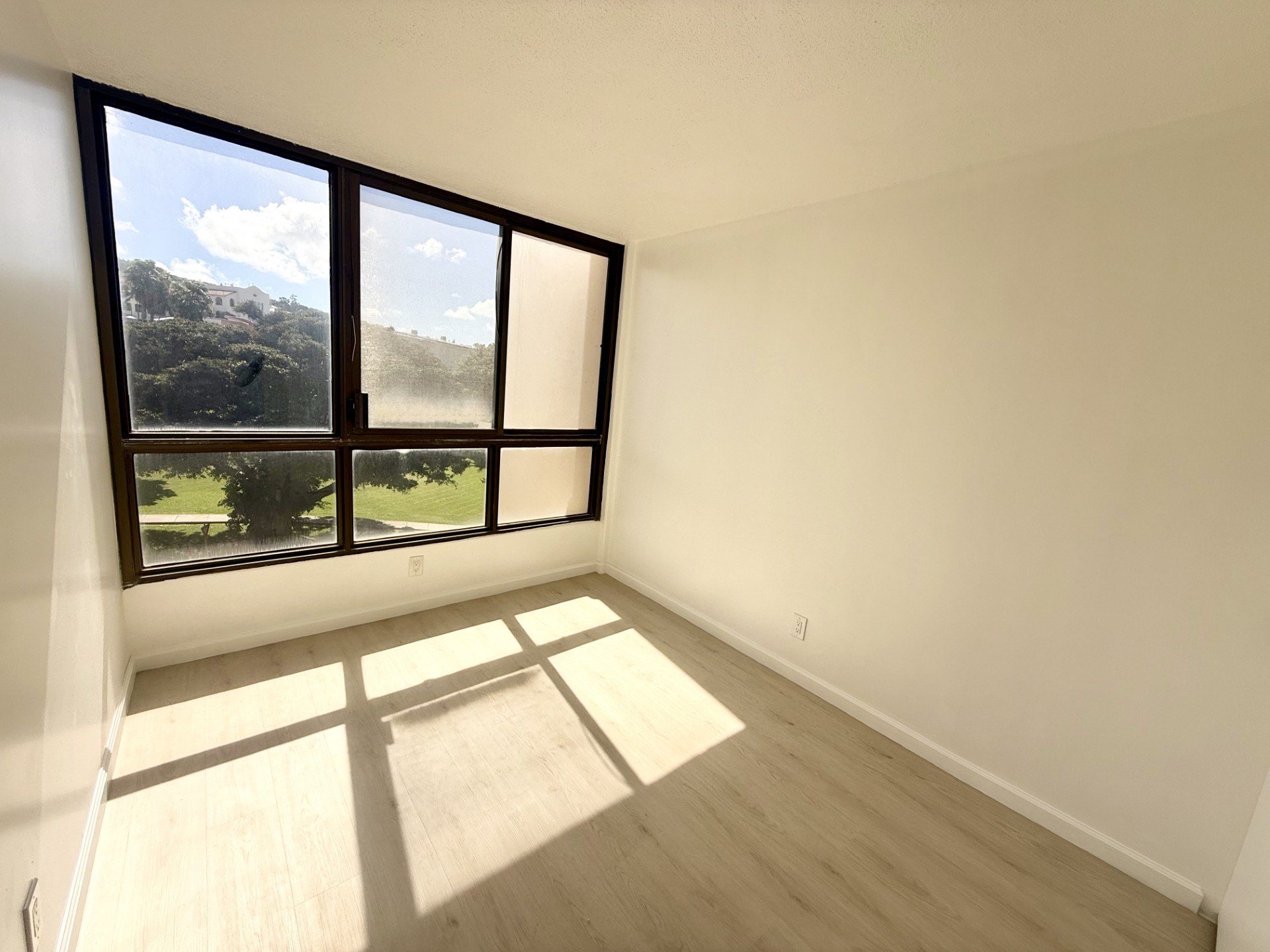 A room with a large window overlooking a green landscape.