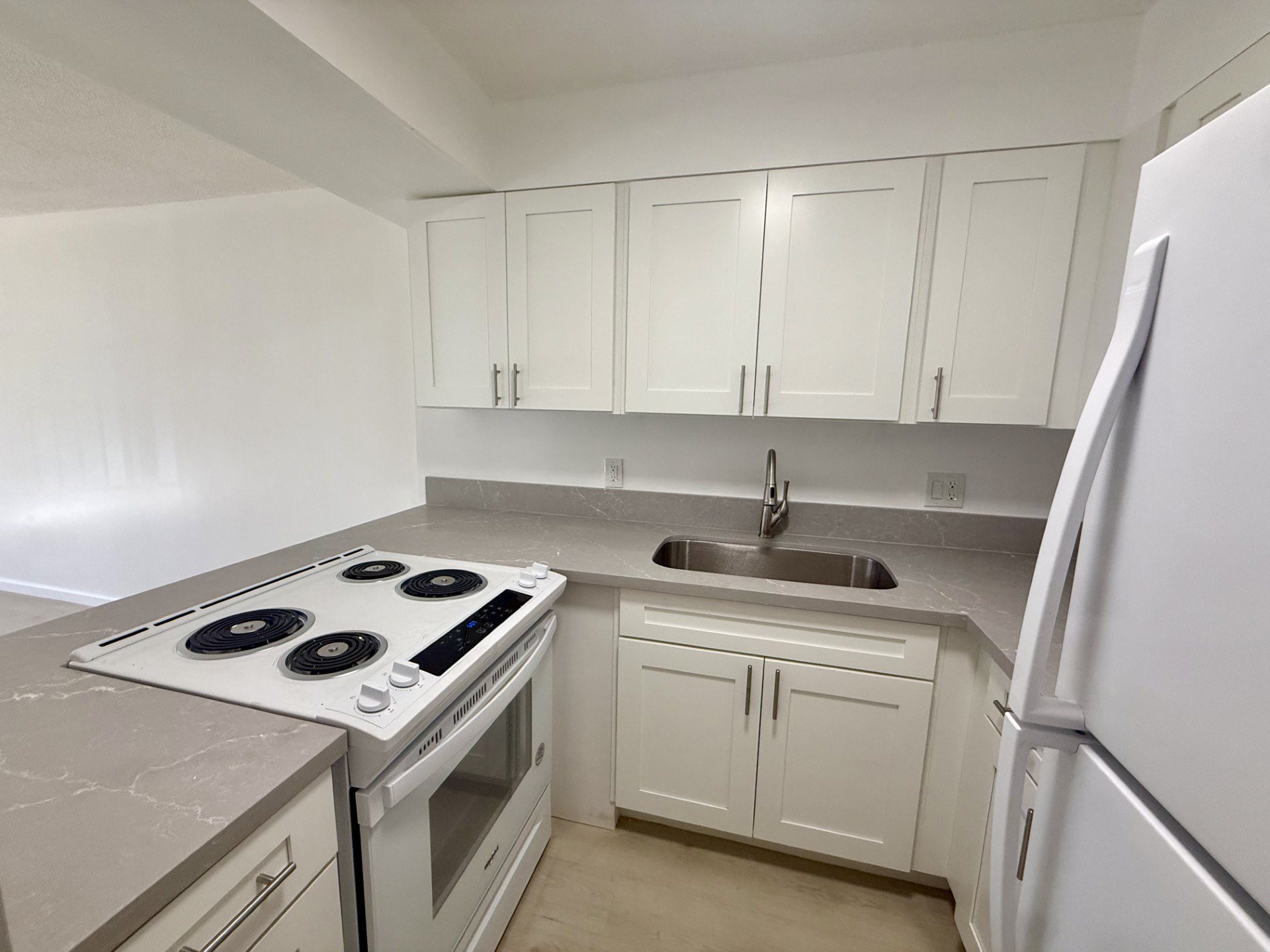 A kitchen with white cabinets and a stove top oven.
