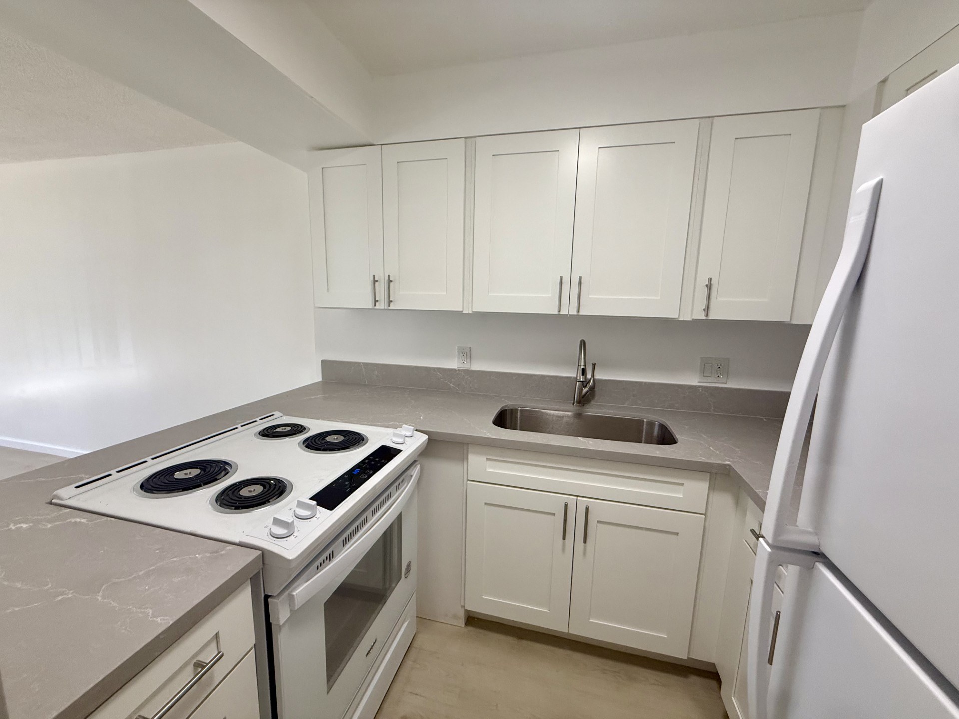 A kitchen with white cabinets and a stove top oven.