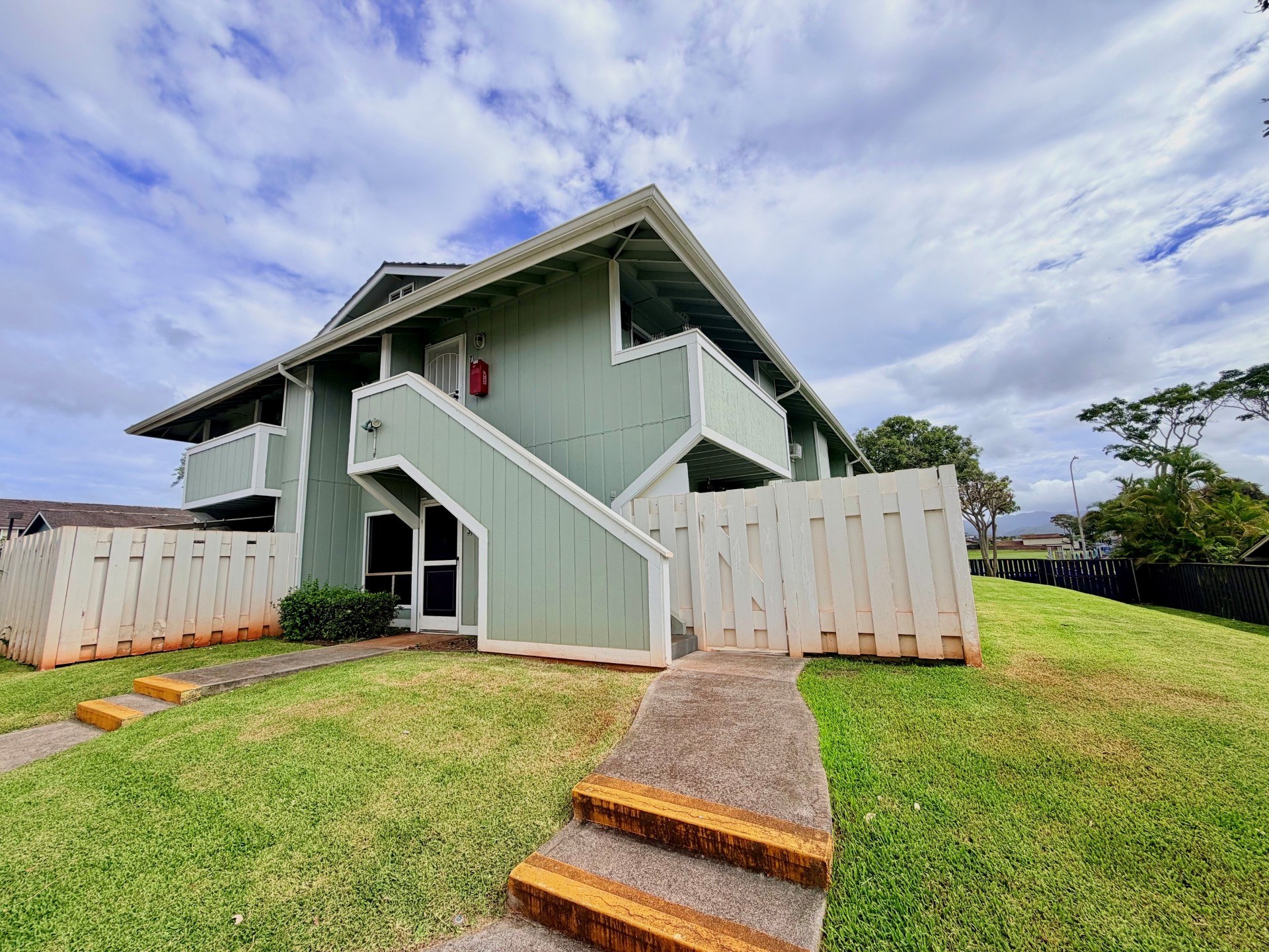 A house with a green exterior and a red fire extinguisher on the wall.