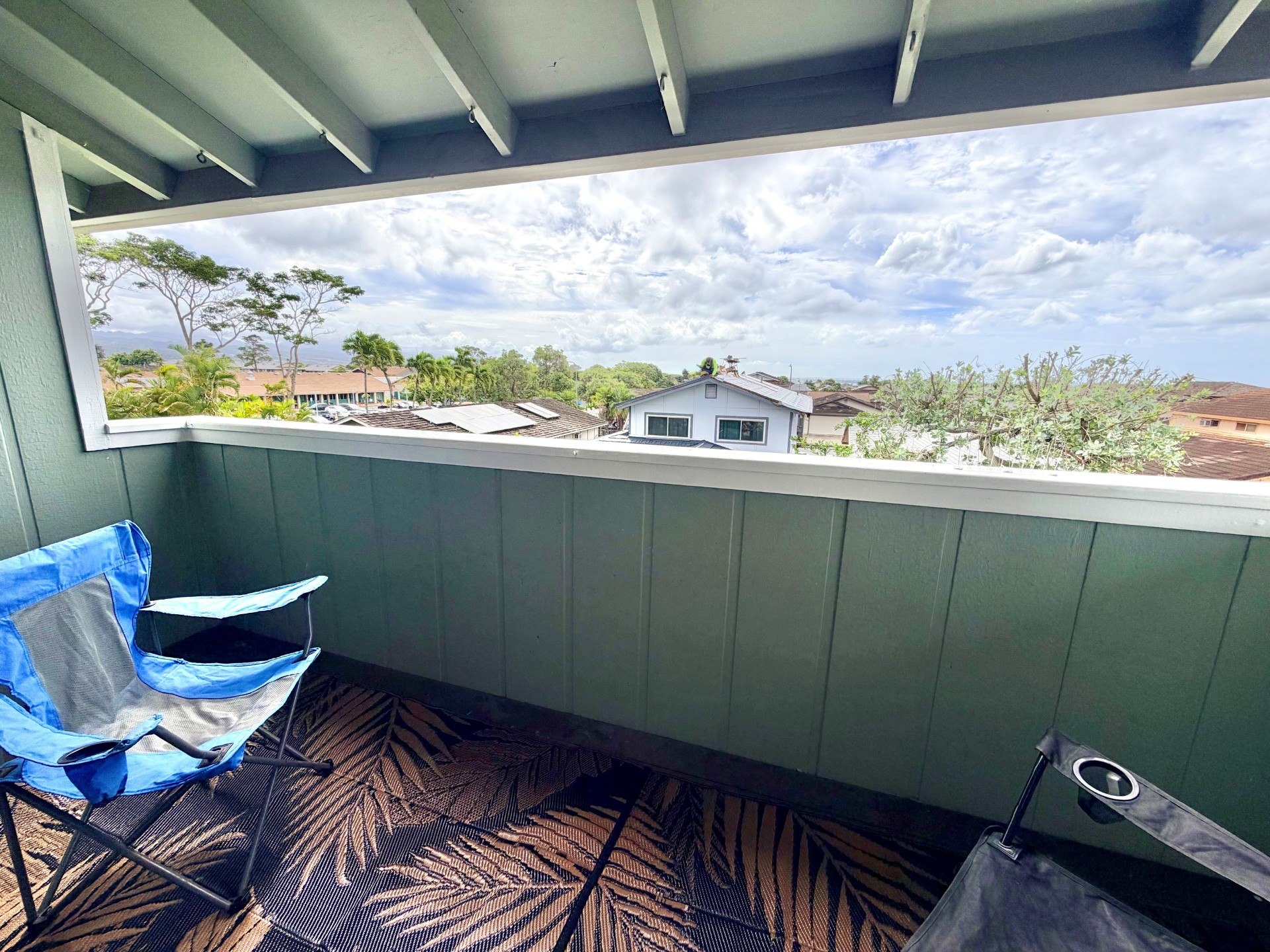 A blue and white chair sits on a patterned carpet on a balcony.