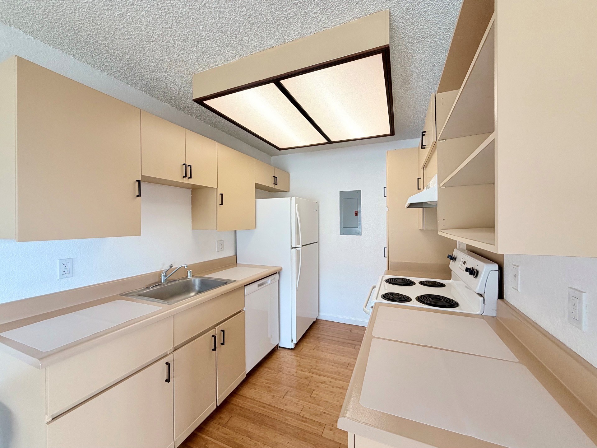 A kitchen with white appliances and beige cabinets.