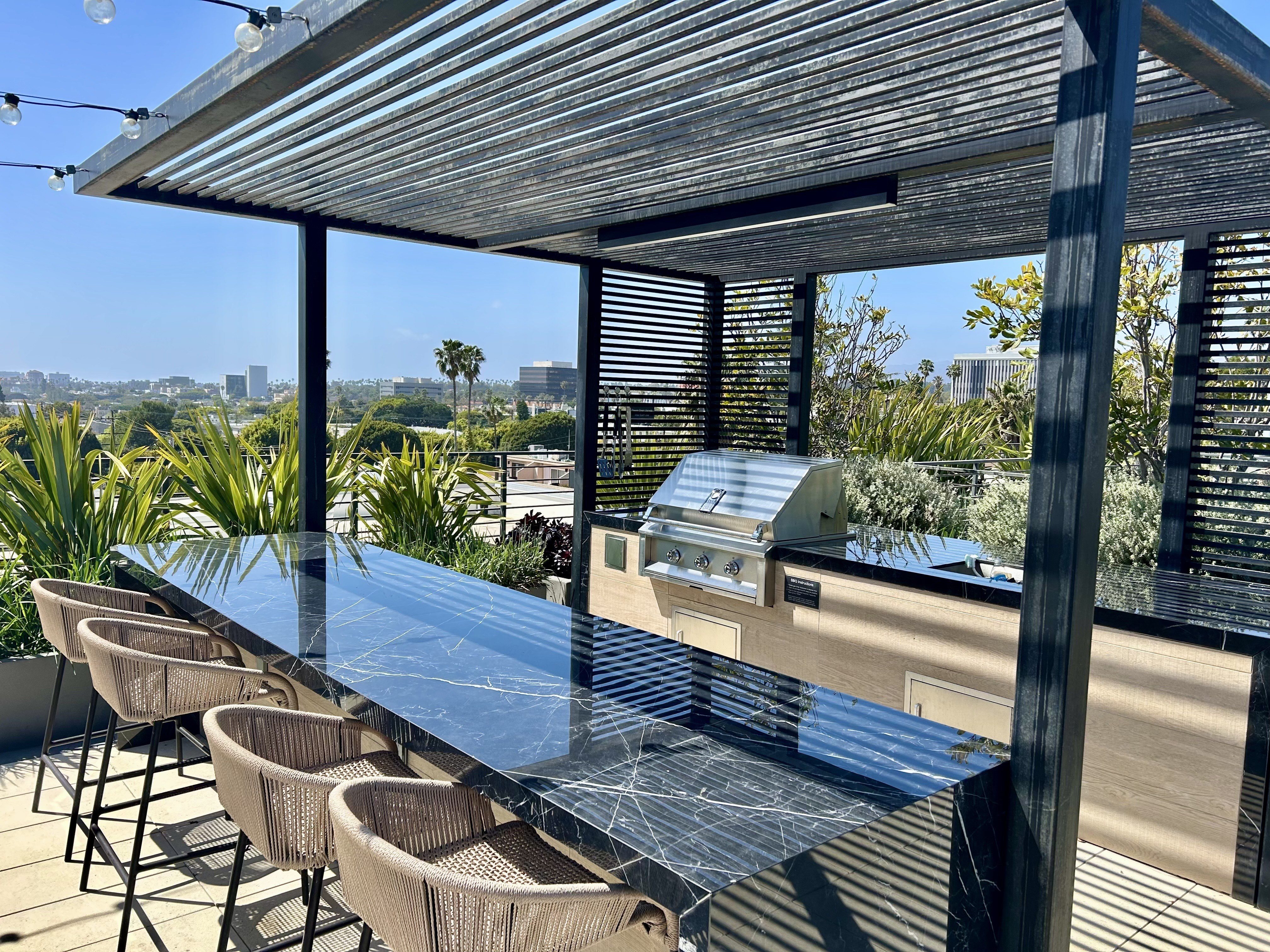 A long table with chairs and a grill on a patio.