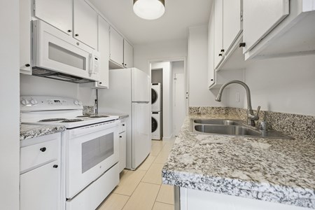 A kitchen with white appliances and a marble countertop.