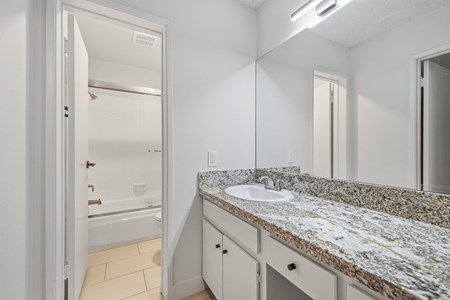 A bathroom with a granite countertop and a white sink.