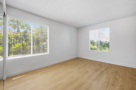 A room with wooden floors and two windows.