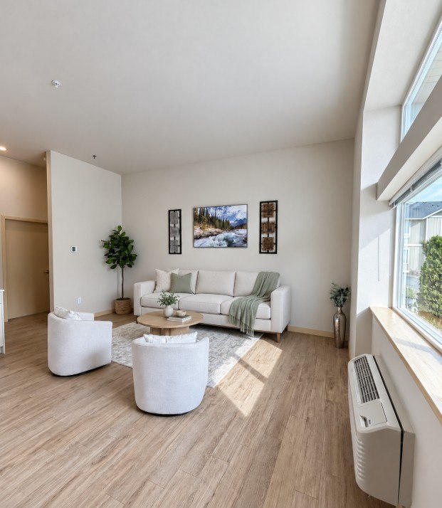 A living room with a white couch, a green blanket, and a white coffee table.