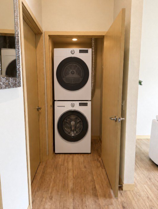 A white dryer is in a small closet.