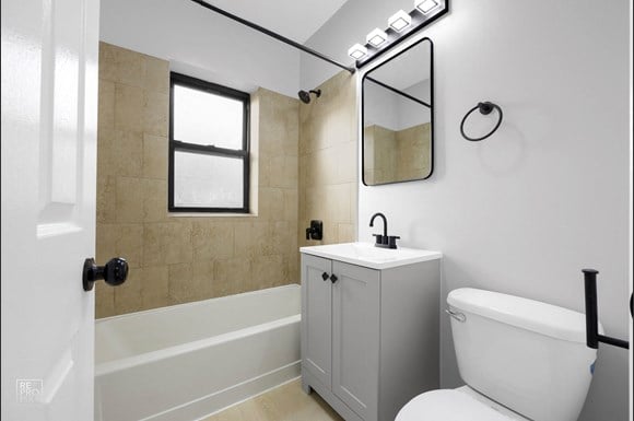 a bathroom with tiled walls and flooring and a white toilet and sink