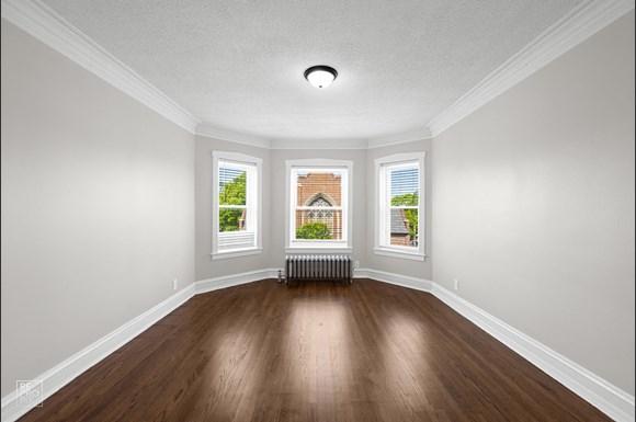 an empty room with hardwood floors and three windows