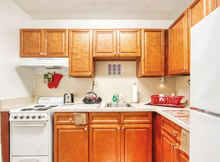 kitchen with white appliance package, wood cabinetry, and model decor