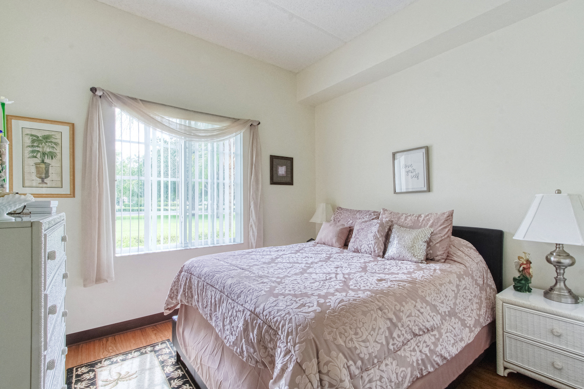 bedroom with large window, hardwood-style flooring, and model furnishings