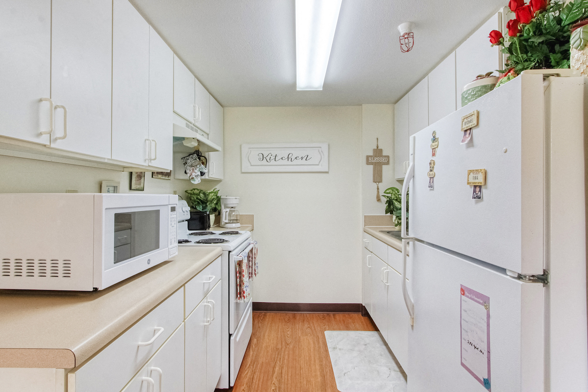 kitchen with white cabinets and appliances at Holy Cross Manor I