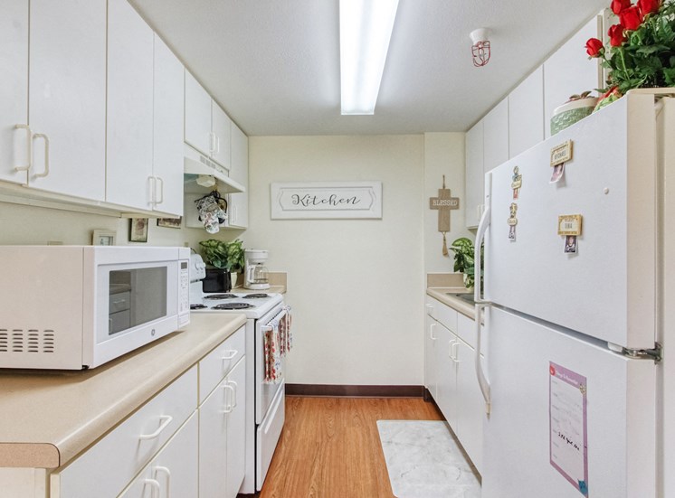 kitchen with white cabinets and appliances at Holy Cross Manor I