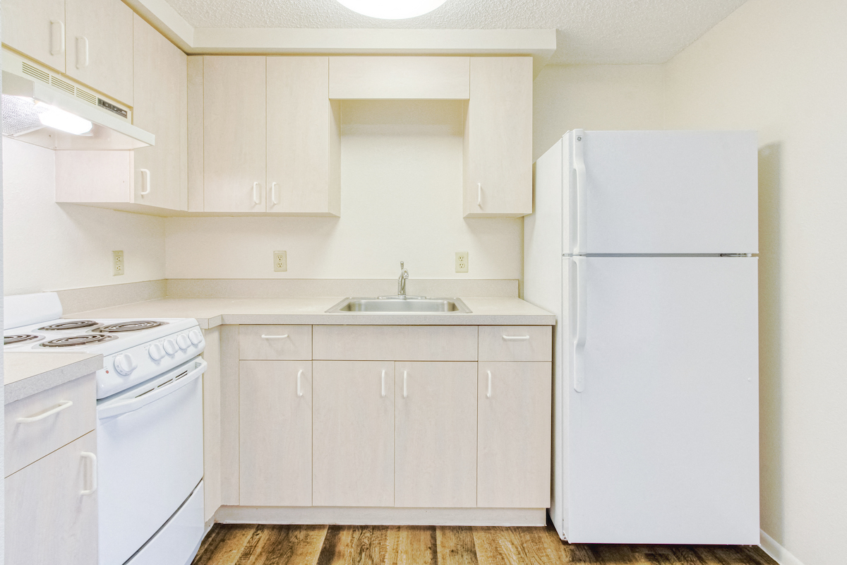 Residential kitchen with white appliances, ample cabinetry, and hardwood-style flooring
