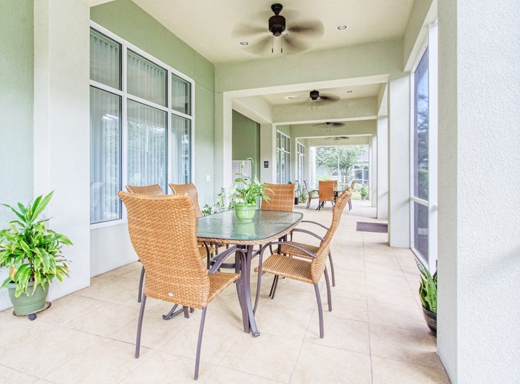 Screened in community patio with outdoor tables, chairs, and ceiling fans
