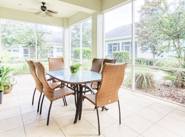 screened in community patio with ceiling fan and outdoor dining table and chairs