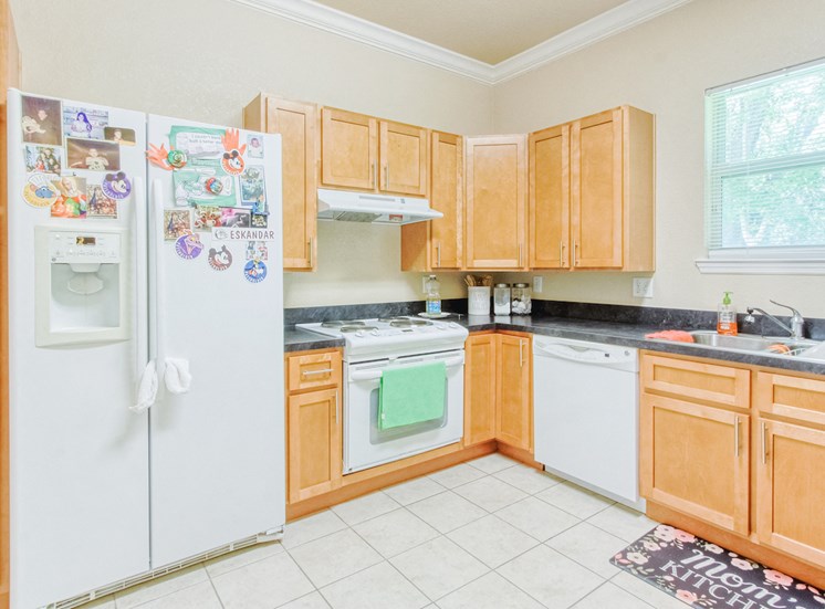 Kitchen with ample cabinetry, white appliances, and double stainless steel sink
