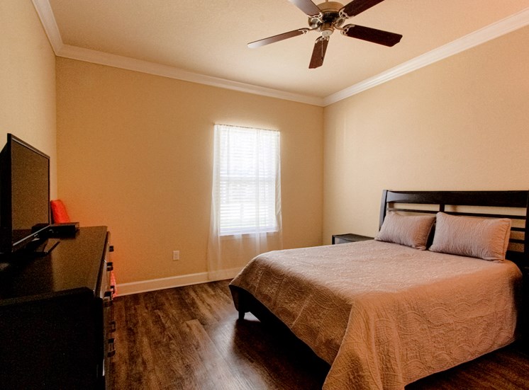 bedroom with hardwood style flooring, ceiling fan, window, and model furniture