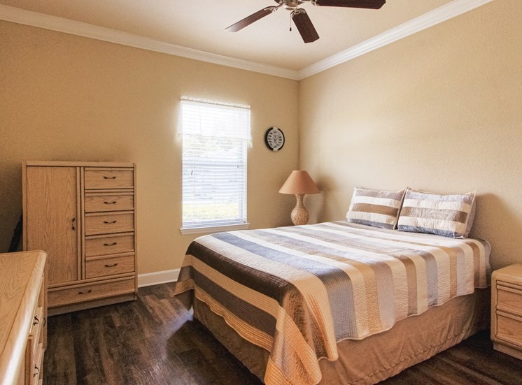 bedroom with ceiling fan, hardwood-style flooring, window, and model decor
