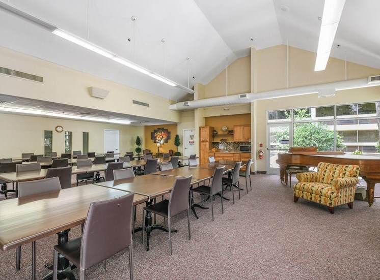 community room with rows of tables and chairs and a piano at Sundale Manor Apartments