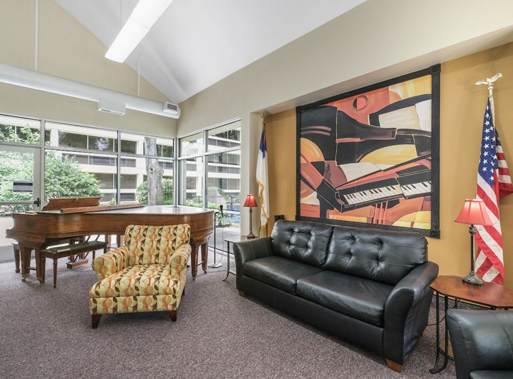 community room with large painting, couch, chairs, American flag, and piano