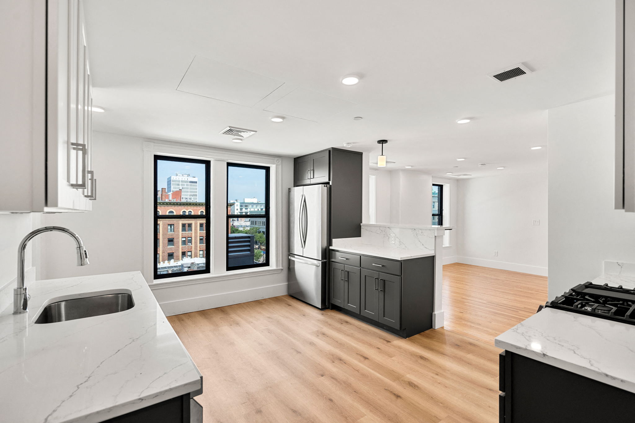 a kitchen with white countertops and black appliances and a large window