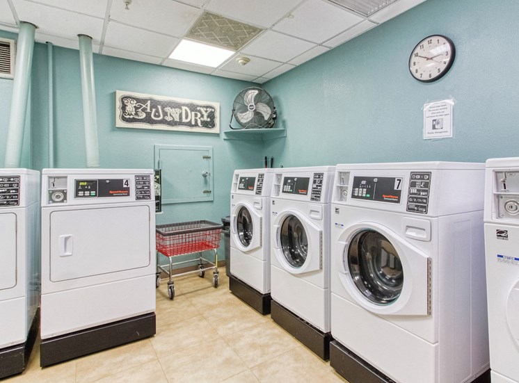 laundry room with washers and dryers, rolling cart, fan, and coin machine