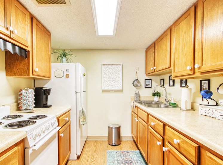 galley kitchen with ample cabinetry, white appliances, and wood-style floors