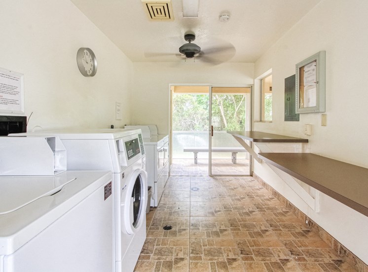 laundry room with washers, dryers, folding tables, and ceiling fan
