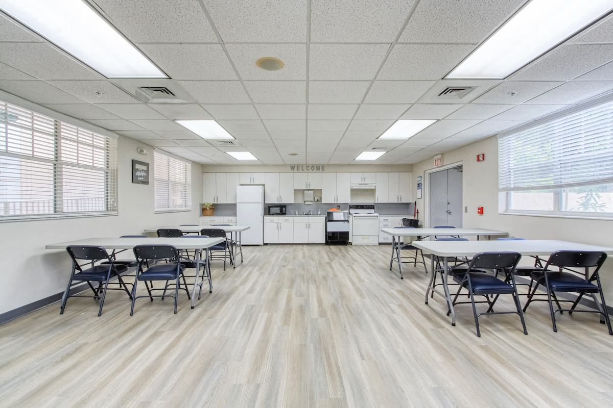community room with kitchen and tables and chairs for residents