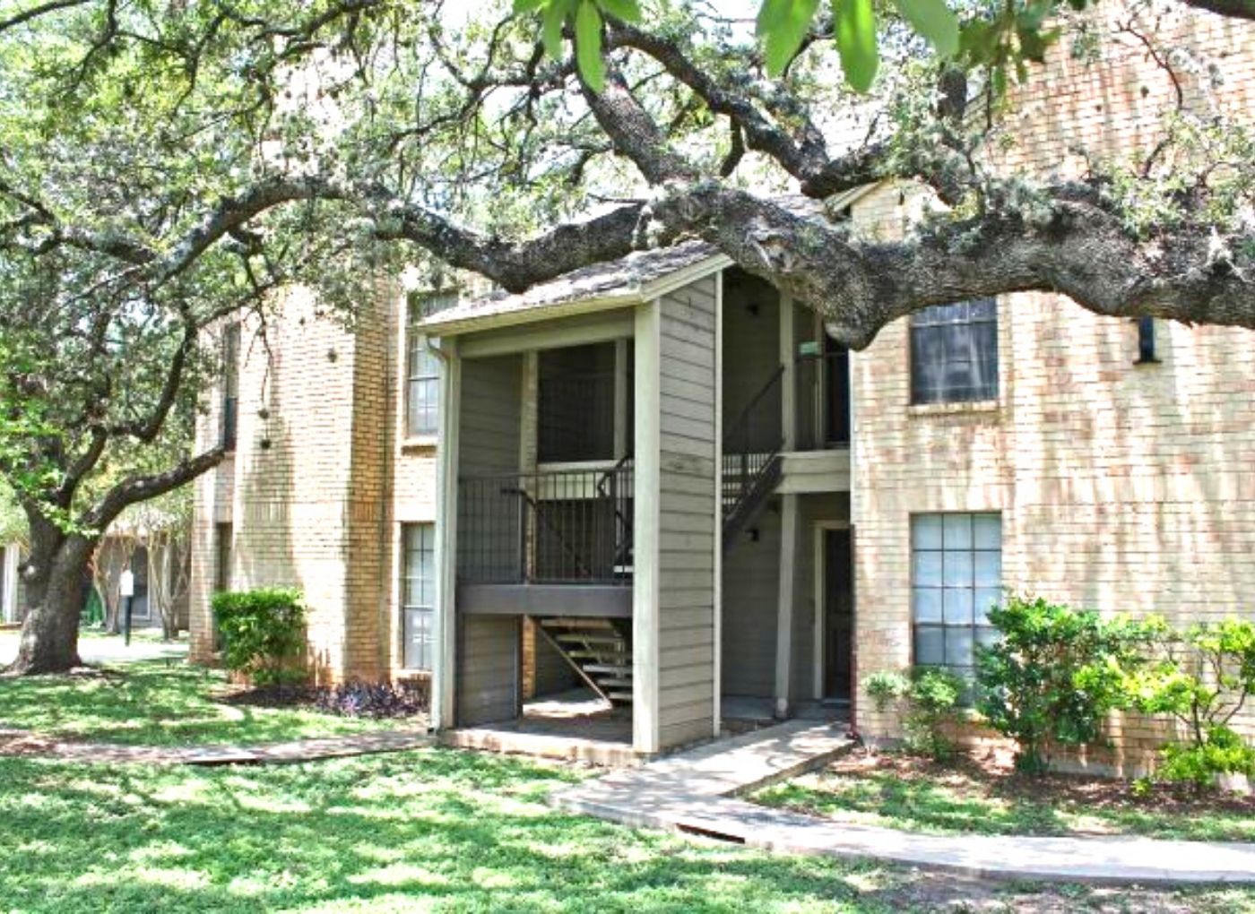 building exterior with cream colored brick and green landscaping