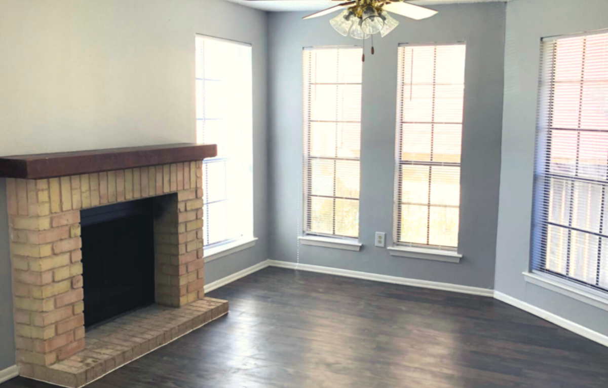 Living room with dark wood floors, brick fireplace with cherrywood mantle, and 4 wall length mirrors