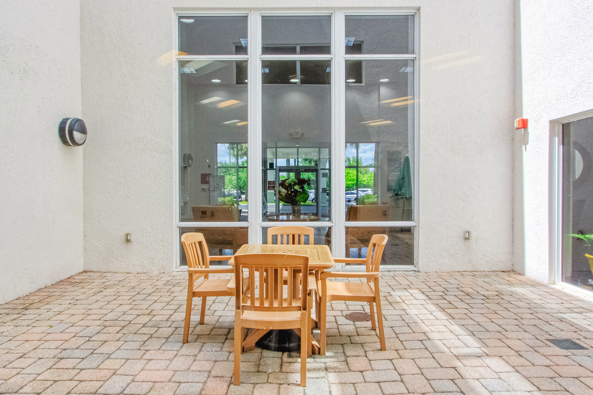 table and chairs on outside patio beside large window