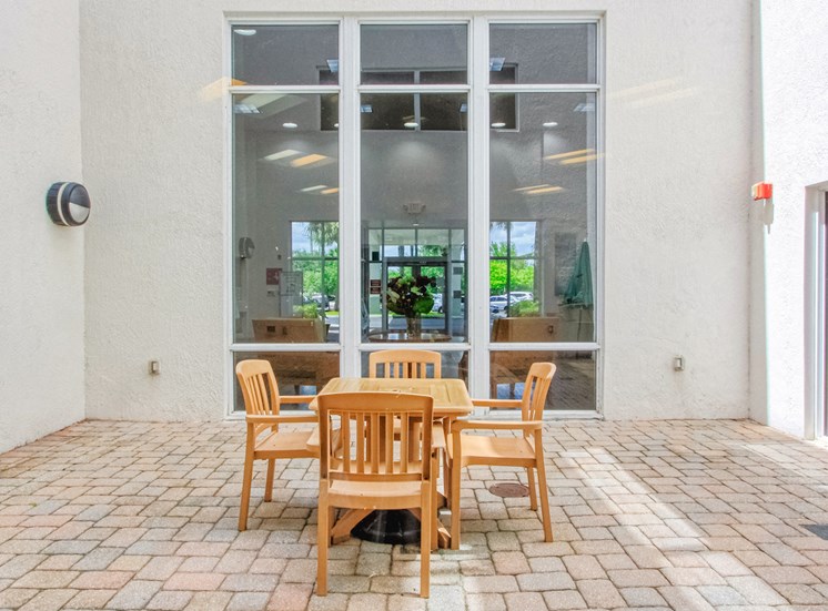 table and chairs on outside patio beside large window