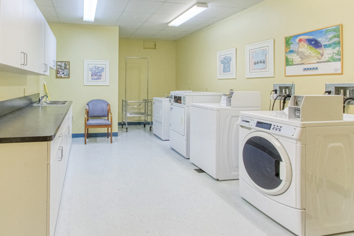 laundry center with washers, dryers, and folding tables