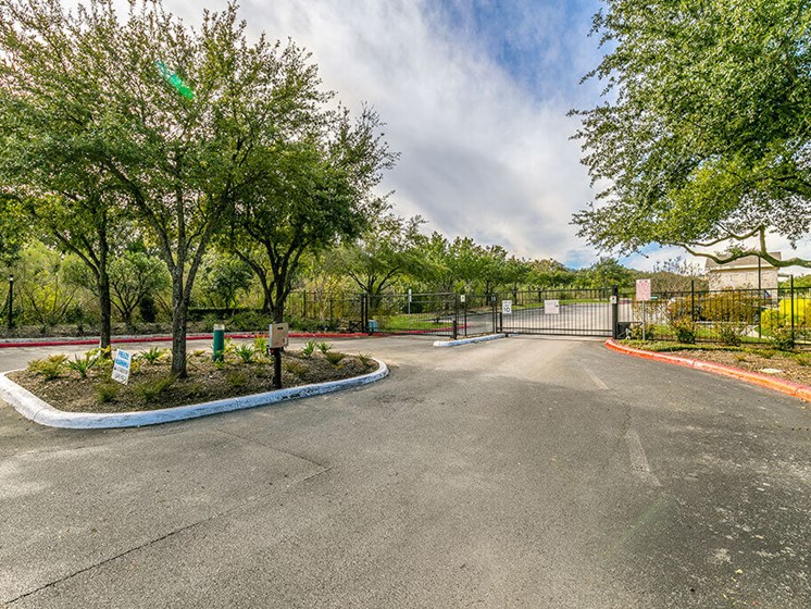 Gated community entrance with trees and circle drive