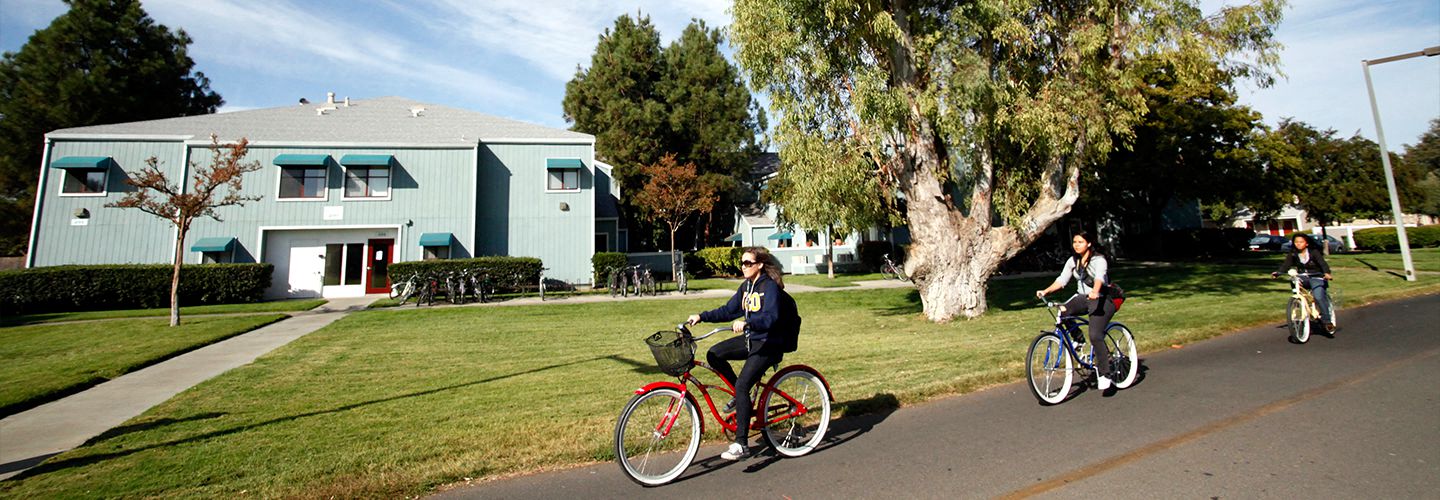 Student biking on the green belt near The Atriums